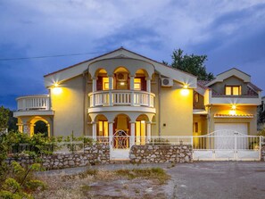 A two-story house with a balcony, a stone wall in front, and a gated driveway. - Vacation home  by Interhome (Donje Rastane)