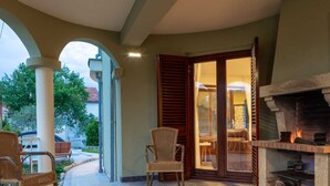 Eine Terrasse mit Kamin, Korbstühlen und Blick ins Freie.