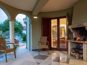 A patio area with a fireplace, wicker chairs, and a view of the outside. - Vacation home  by Interhome (Donje Rastane)