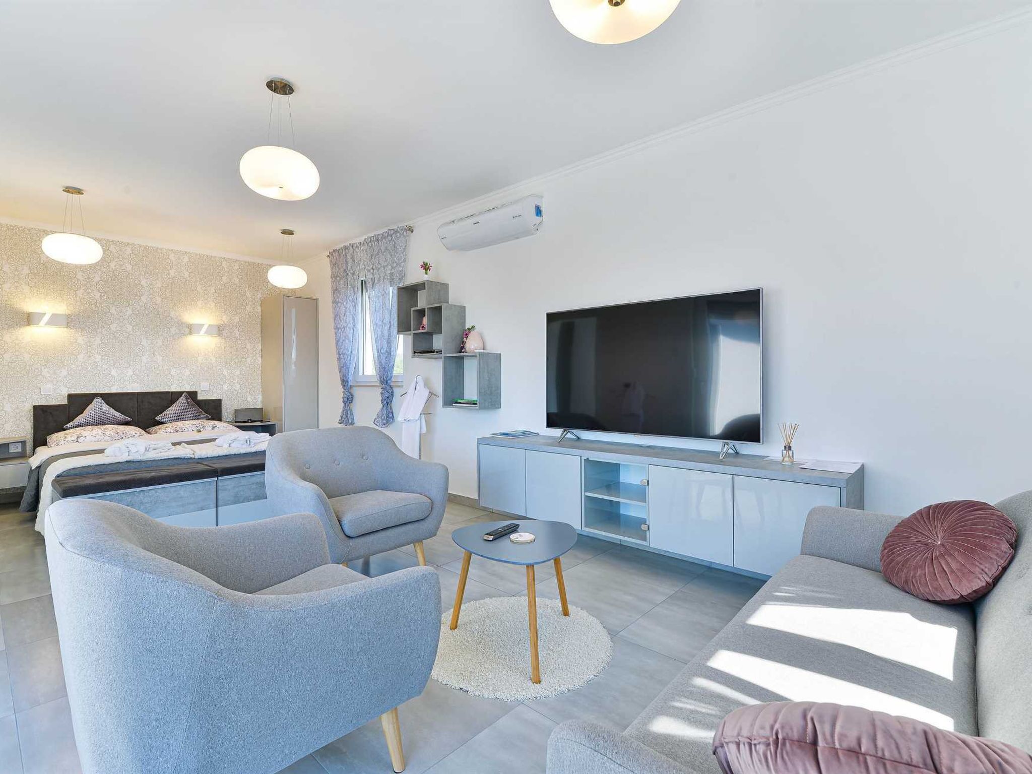 A modern living room with a sofa, armchairs, a coffee table, and a TV.