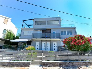 A modern two-story house with a balcony, a garage, and a garden with red flowers. - Apartment  by Interhome (Donje Rastane)