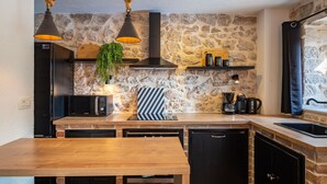 Eine Küche mit Steinwand, Holzausziehtisch und modernen Geräten.