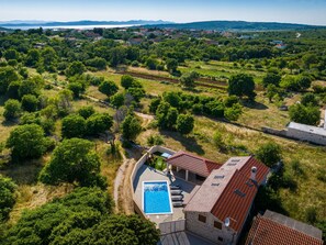 Un quartier résidentiel doté d’une piscine, entouré de verdure et offrant une vue sur des collines lointaines.