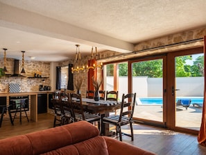 Un coin repas avec une table et des chaises, une cuisine avec un mur en pierre et une vue sur une piscine.