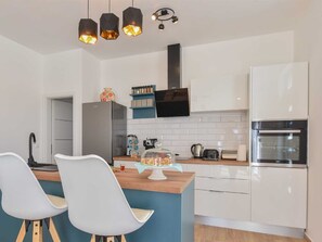 A modern kitchen with white cabinets, a central island with chairs, a stove, and a microwave. - Villa Silente with pool and sauna by Interhome (Debeljak)