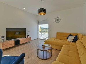 A modern living room with a sofa, TV, and a small table with a glass of juice. - Villa Silente with pool and sauna by Interhome (Debeljak)