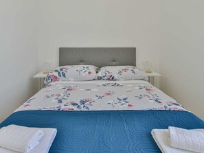 A bed with a floral duvet, a grey headboard, and two bedside tables with lamps. - Villa Silente with pool and sauna by Interhome (Debeljak)