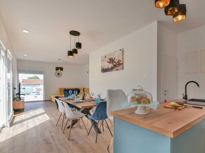 A modern kitchen with a wooden island, a dining area with chairs, and pendant lighting. - Villa Silente with pool and sauna by Interhome (Debeljak)