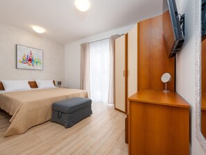 A hotel room with a bed, a desk, a chair, a small ottoman, a TV, and a window with curtains. - Villa Paloma with heated pool by Interhome (Debeljak)