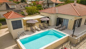Una piscina con lettini e ombrelloni, immersa in un quartiere residenziale.