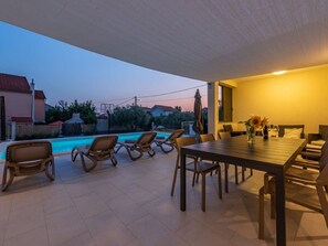 An outdoor patio with a pool, lounge chairs, and a dining table with chairs. - Villa Paloma with heated pool by Interhome (Debeljak)