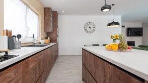 Una cucina moderna con mobili in legno, un'isola centrale con della frutta e una sveglia a parete.