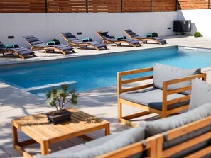 Ein Poolbereich mit Liegestühlen und einem Tisch mit einer Pflanze.