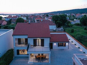 A two-story house with a red-tiled roof, a balcony, and a view of a residential area. - Villa Marta with heated pool and traditional taver by Interhome (Debeljak)