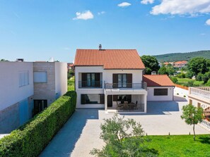 Ein zweistöckiges Haus mit rotem Ziegeldach, einem Balkon und einem gepflasterten Innenhof.