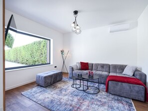 A modern living room with a grey sofa, a small round table, a grey ottoman, and a patterned rug. - Villa Marta with heated pool and traditional taver by Interhome (Debeljak)
