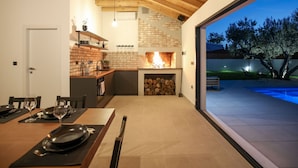 Eine moderne Küche mit Backsteinwand, Kamin und Essbereich mit Tisch für zwei Personen.