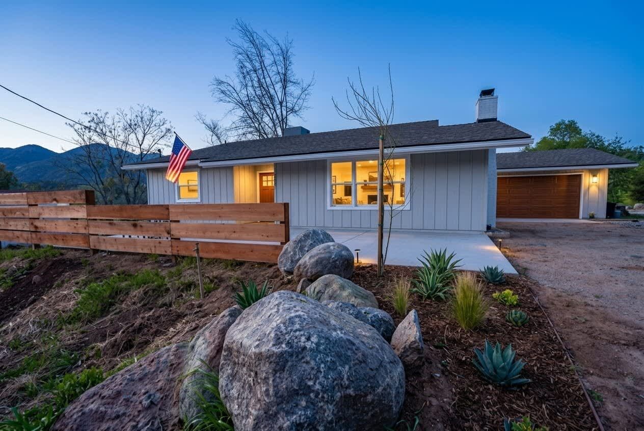 A single-story house with a garage, a wooden fence, and a flag.