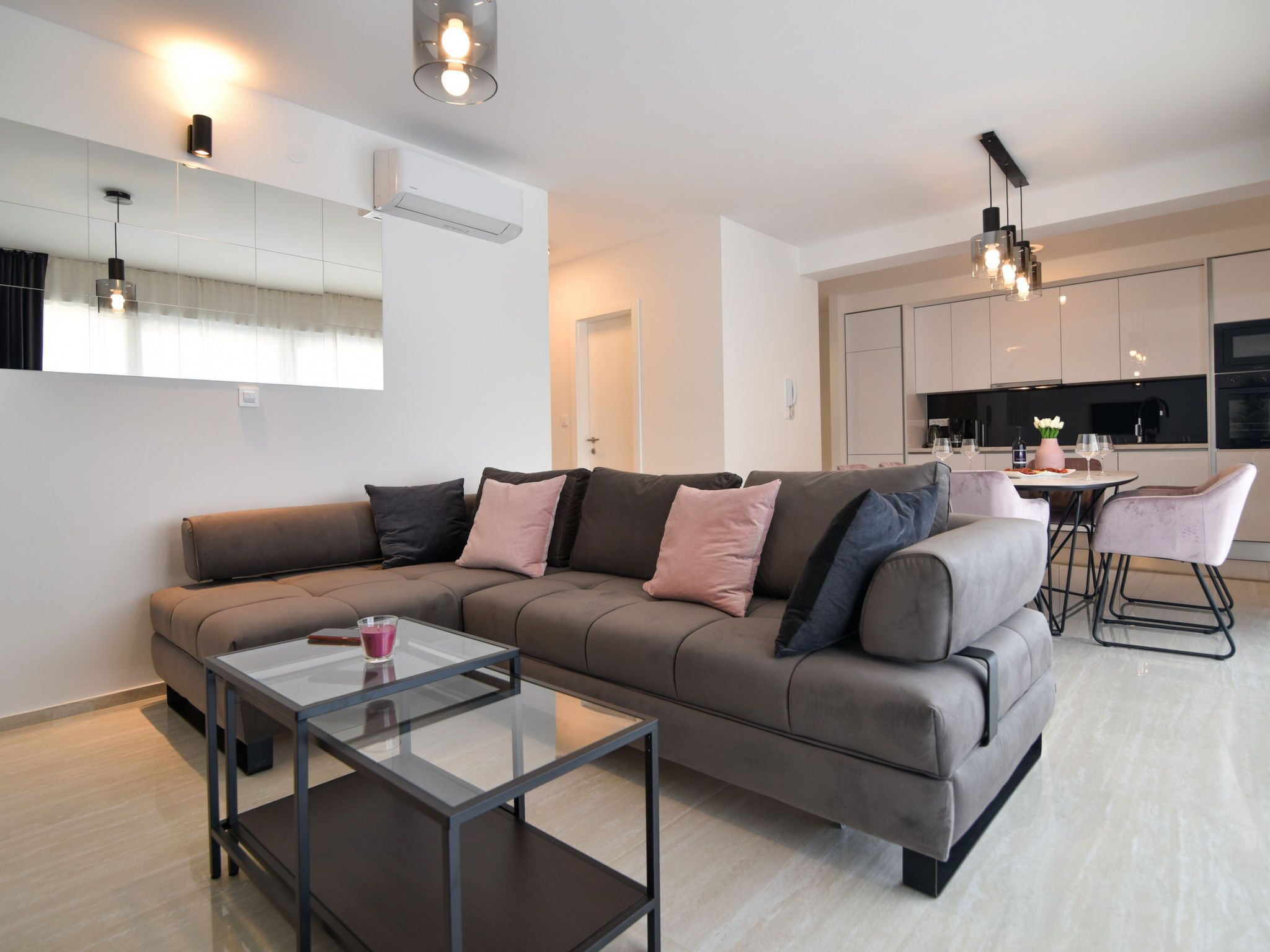 Un salon moderne avec un canapé, une table basse en verre et une cuisine en arrière-plan.