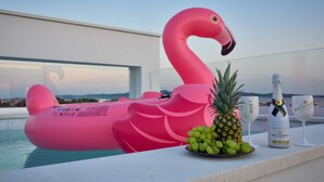 A poolside setting with a pink flamingo float, a bottle of champagne, and a glass. - Apartment  by Interhome (Zadar/Bibinje)