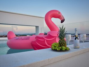 Ein Poolbereich mit einem Flamingo-Schwimmpunkt, einer Champagnerflasche und einem Glas.