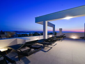 Ein Außenbereich mit Lounge-Möbeln und Tischen, einer Pergola und Blick auf die Landschaft.
