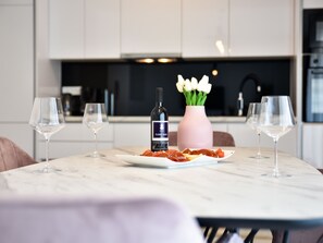 Cocina moderna con encimera de mármol, una botella de vino, un jarrón con flores y un plato de comida.