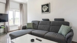 A modern living room with a grey sofa, a white coffee table, a remote control, and a framed artwork on the wall. - Vacation home  by Interhome (Crno)