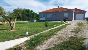 A residential house with a red-tiled roof, a grey facade, and a front yard with a pathway leading to the entrance. - Holiday house Flora with pool by Interhome (Crno)