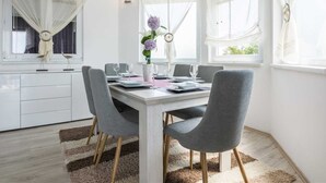 A modern dining area with a white table, grey chairs, and a vase of flowers. - Holiday house Flora with pool by Interhome (Crno)