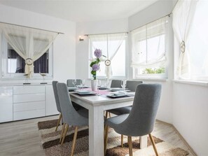 Ein stilvoller Essbereich mit einem weißen Tisch, grauen Stühlen und einem Blumenstrauß.