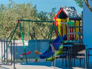 Ein Spielplatz mit Schaukeln, einer Rutsche und einer Kletterkonstruktion.
