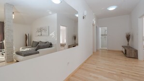 A spacious living area with a modern sofa, a large mirror reflecting the room, and a wooden floor. - Beautiful villa Horizon by Interhome (Crno)