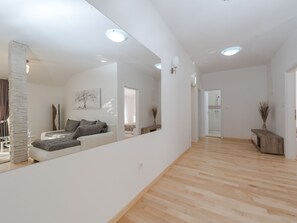 Ett rymligt vardagsrum med en modern soffa, en stor spegel som reflekterar rummet och ett trägolv.