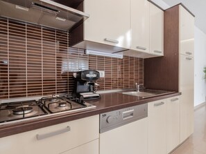 Ett modernt kök med en gasspis, kaffebryggare och diskmaskin.