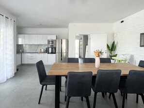 Cozinha moderna com armários brancos, uma mesa de jantar de madeira e cadeiras pretas.