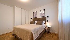 Une chambre à coucher avec un lit, une table de chevet avec une lampe et deux tableaux encadrés accrochés au mur.