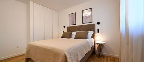 A bedroom with a bed, a bedside table with a lamp, and two framed pictures on the wall.
