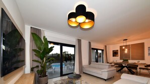 Un salon moderne avec un canapé, une table basse et un téléviseur. Il y a également un coin repas avec une table et des chaises.
