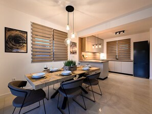 Eine moderne Küche mit Essbereich, ausgestattet mit einem Holztisch, schwarzen Stühlen und Pendelleuchten.