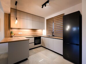 A modern kitchen with a black refrigerator, wooden cabinets, and a built-in oven. - Villa Nostro Porto with pool by Interhome (Crno)
