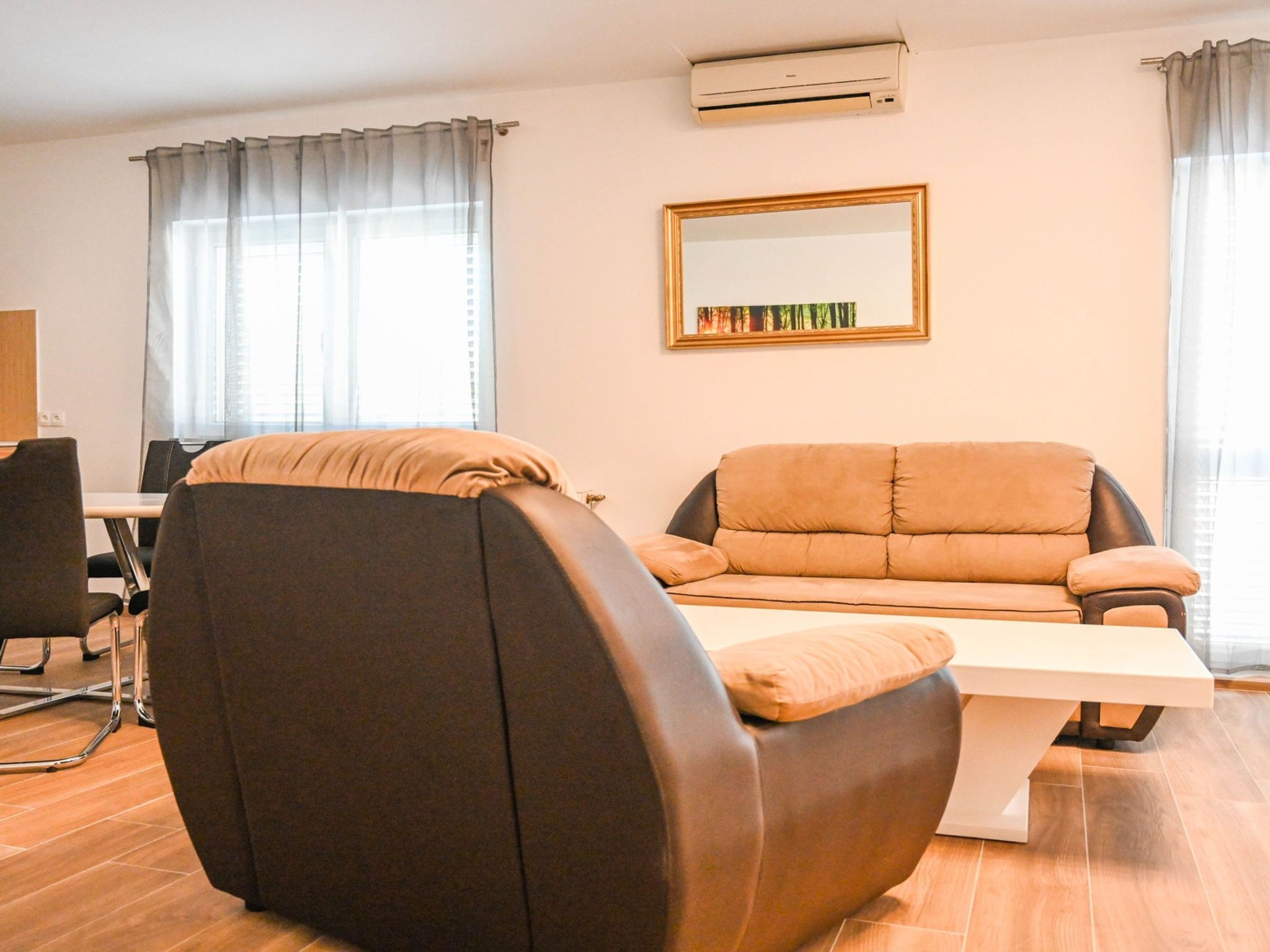 Un salon moderne avec un canapé, un fauteuil, une table et un grand miroir au mur.