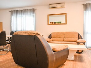 Een moderne woonkamer met een bank, een stoel, een tafel en een grote spiegel aan de muur.