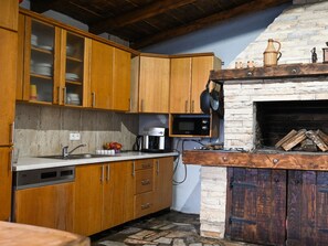 A kitchen with wooden cabinets, a stone wall, a built-in microwave, and a fireplace. - Holiday Home Urbana with pool by Interhome (Crno)