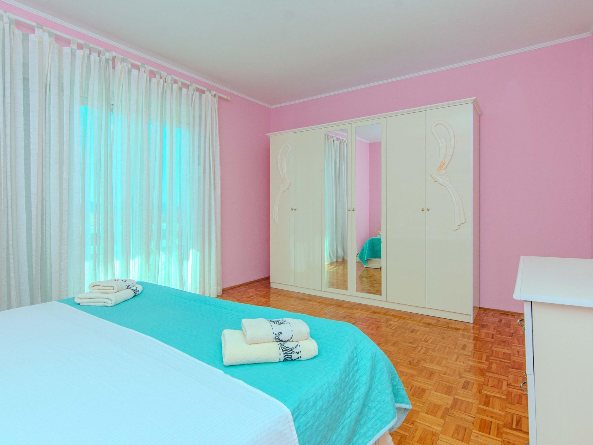 A bedroom with a bed, a wardrobe, and a mirror.