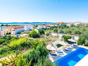 A residential area with a swimming pool, lounge chairs, and a view of the sea. - Villa Annamaria with large pool, Zadar by Interhome (Crno)