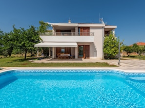 Une maison à deux étages avec une piscine à l’avant.