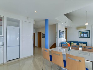 A modern kitchen with a refrigerator, a dining table with chairs, and a blue accent wall. - Vacation home  by Interhome (Privlaka)