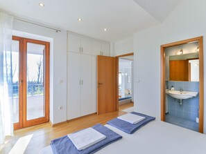 A bedroom with a large wardrobe, a bathroom with a sink, and a view of the outdoors. - Vacation home  by Interhome (Privlaka)
