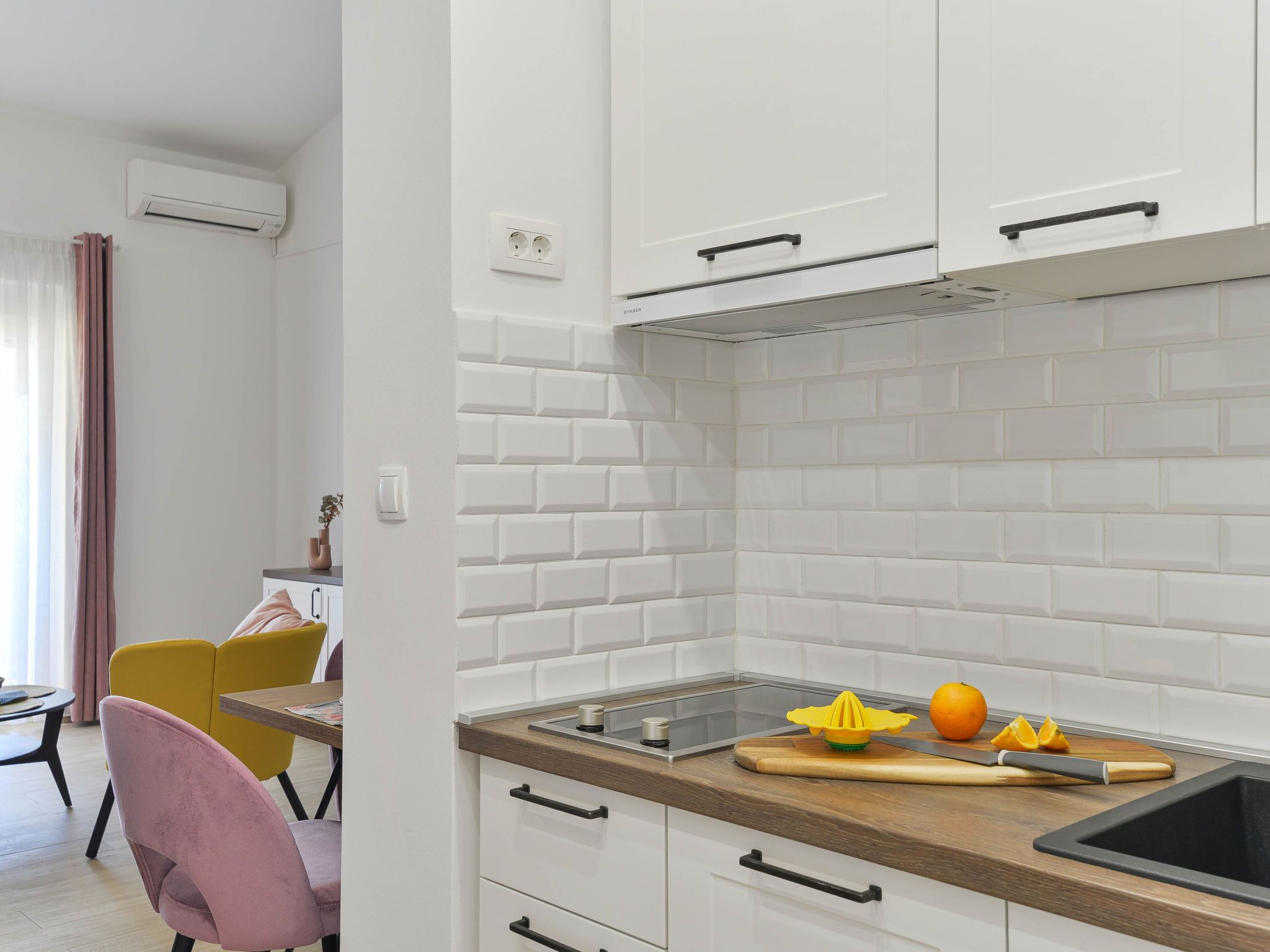 A modern kitchen with white cabinets, a stainless steel countertop, and a built-in oven.